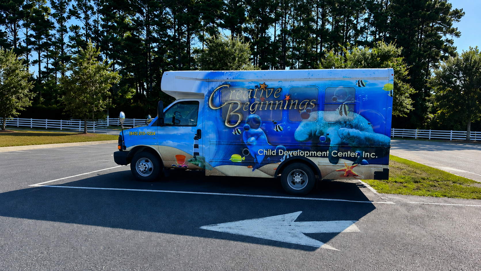 Creative Beginnings Child Development Center bus with colorful ocean-themed wrap parked outside